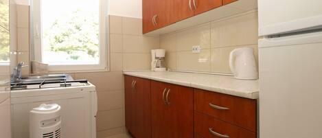 Una cocina con armarios de madera, encimera blanca, cafetera y electrodoméstico blanco.