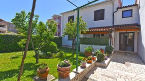 A residential building with a garden, potted plants, and a tiled patio area. - Apartment 1230 (Pula)