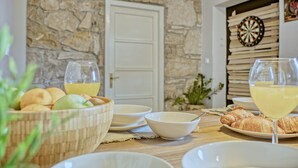 A dining table with plates, bowls, glasses of yellow beverage, and croissants. - House 1231 (Pula)
