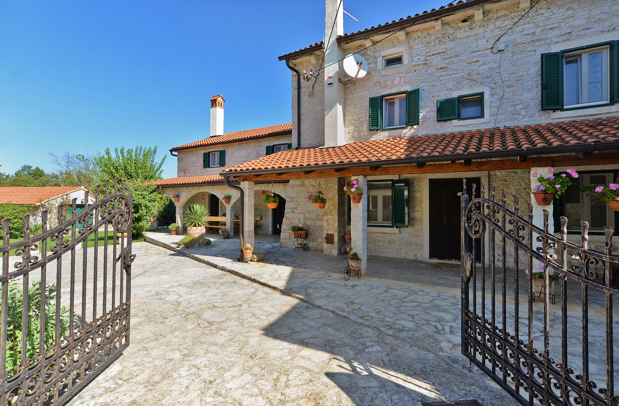 Un bâtiment traditionnel en pierre, doté d’un toit en tuiles, d’une cour intérieure avec des arcades et d’une porte d’entrée.