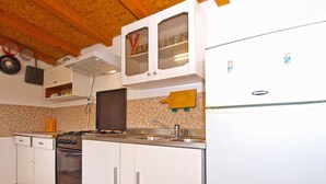 A compact kitchen with white cabinets, a stove, a sink, and a refrigerator. - Apartment 1265 (Fazana)