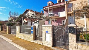 A residential building with a gated entrance, a balcony, and a stone wall. - Apartment 1265 (Fazana)