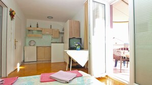 A compact room with a bed, a small kitchenette, a television, and a sliding glass door leading to an outdoor area. - Apartment 1265 (Fazana)
