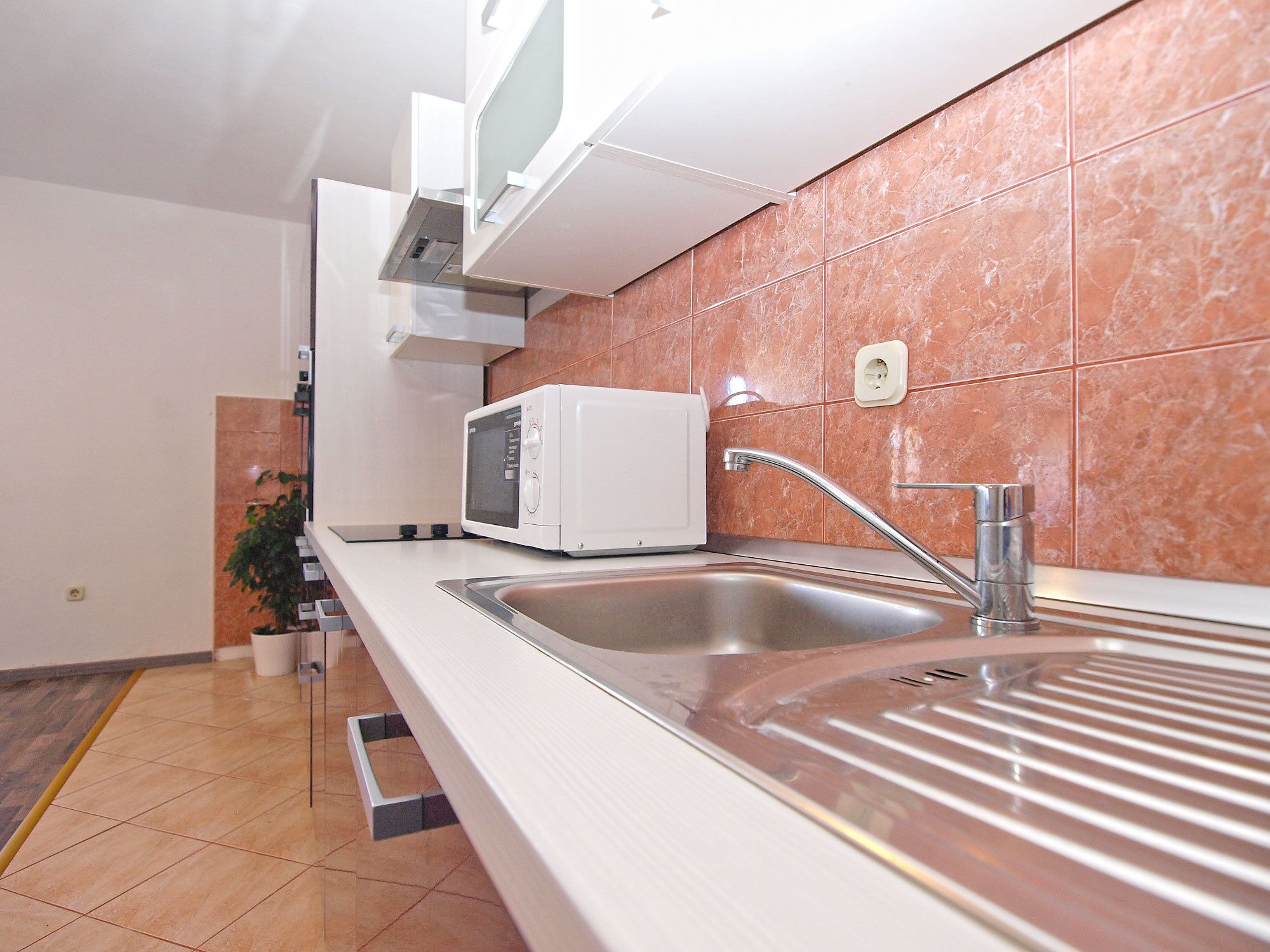 A modern kitchen with a microwave, sink, and stainless steel faucet.