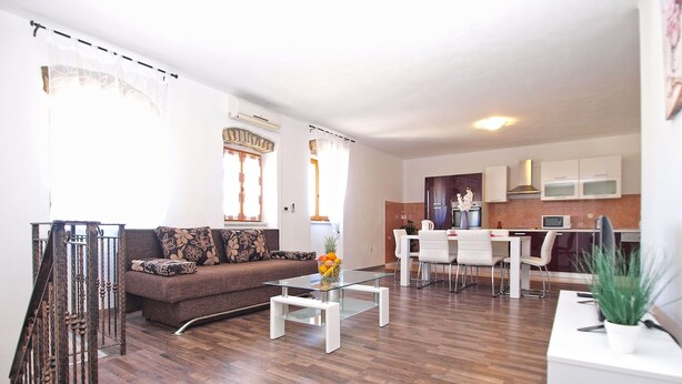 A modern living room with a sofa, coffee table, and dining area. - House 1277 (Visnjan)