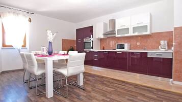 Una cocina moderna con armarios blancos, un microondas y una cafetera.