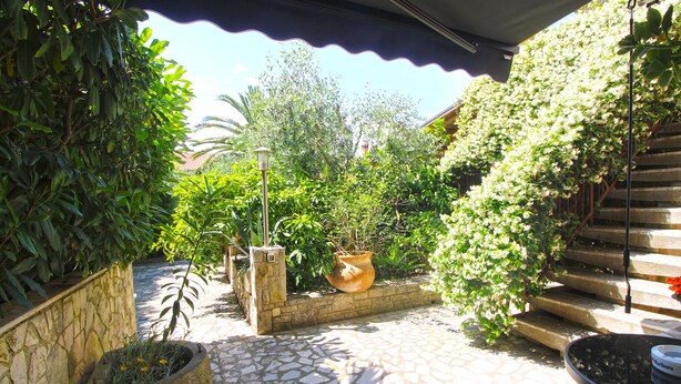 A stone-tiled patio with a potted plant, a large urn, and a metal chair. - Apartment 1278 (Pula)