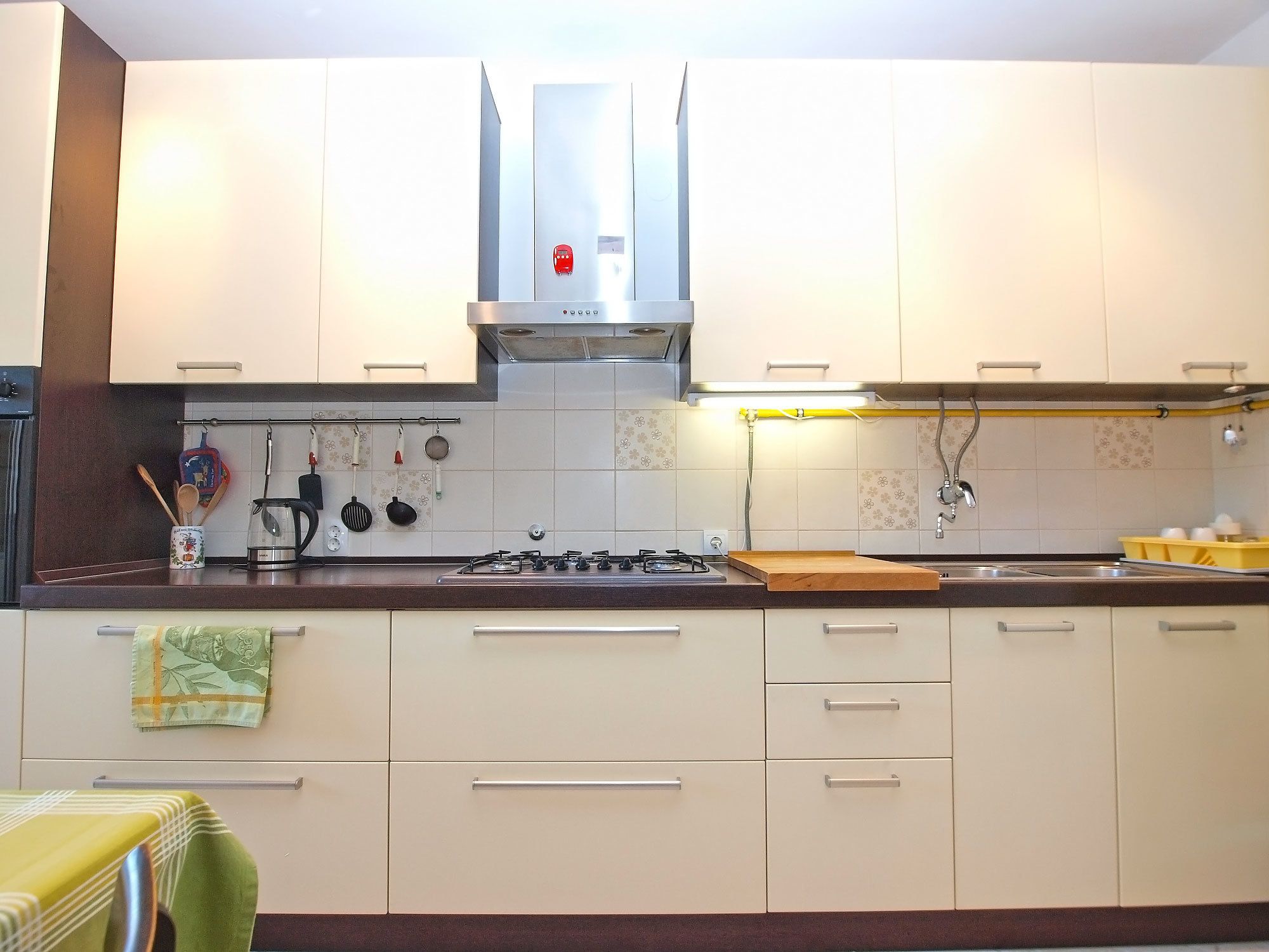 A modern kitchen with white cabinets, a gas stove, and a stainless steel range hood.
