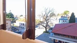 A view from a window overlooking a street with buildings and a tree. - Apartment 1286 (Pula)