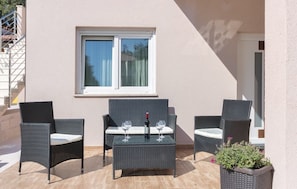 A patio with wicker furniture, a table, and a bottle of wine. - Apartment 1287 (Pula)