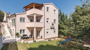Ein mehrstöckiges Wohngebäude mit Balkon, Treppe und einer kleinen Außen-Sitzgelegenheit.