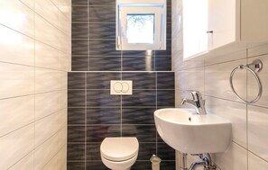 A bathroom with a toilet, sink, and a window above the sink. - Apartment 1287 (Pula)