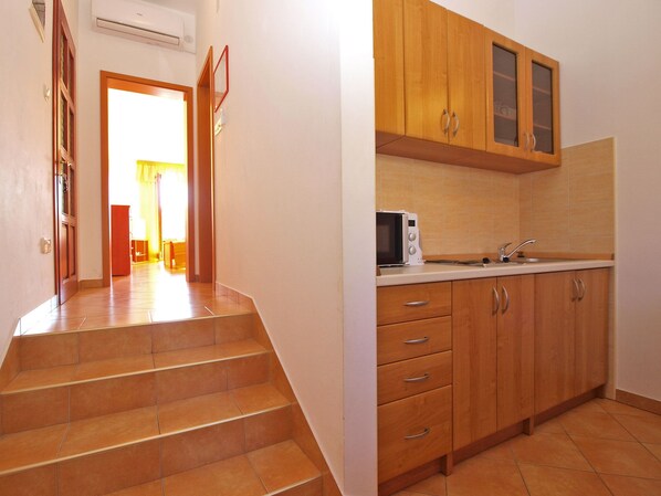 A kitchen with wooden cabinets, a microwave, and a sink. - Apartment 1305 (Pula)