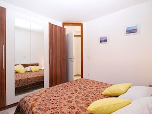 A bedroom with a bed, a wardrobe, and a door leading to another room. - Apartment 1307 (Medulin)