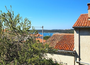 A coastal view with terracotta-tiled roofs, a clear blue sky, and a body of water in the distance. - Apartment 1307 (Medulin)