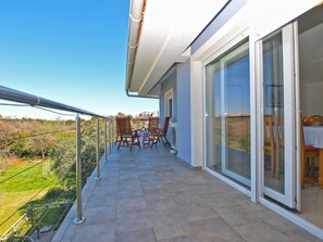 A balcony with a view of the countryside, a table with chairs, and a sliding glass door. - Apartment 1307 (Medulin)