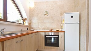 Una cocina con armarios de madera, un lavamanos de acero inoxidable, horno empotrado y refrigerador blanco.