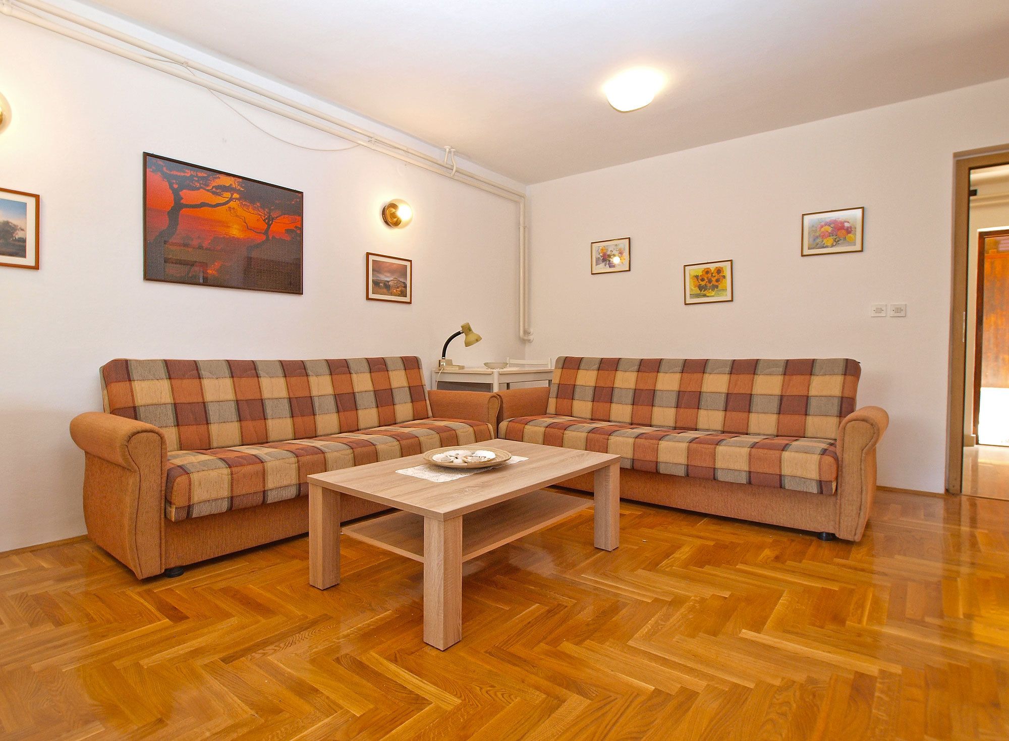 A living room with two plaid sofas, a wooden coffee table, and a painting on the wall.