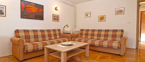 A living room with two plaid sofas, a wooden coffee table, and a painting on the wall.