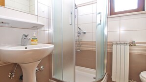 Une salle de bain avec une douche à parois de verre, un lavabo sur colonne et un radiateur.