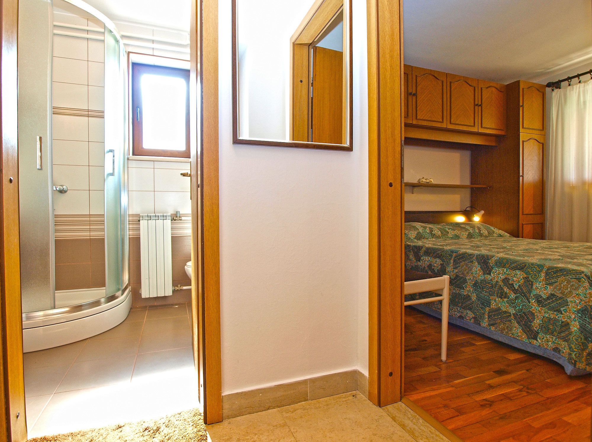Une chambre à coucher comprenant un lit, des armoires en bois, une fenêtre et un espace douche.