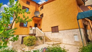 Un immeuble à plusieurs étages, doté d’une façade jaune, d’une antenne parabolique et d’un escalier menant à l’entrée.