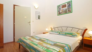 Ein Schlafzimmer mit einem Bett, Nachttischen, einem Wandbild und einer Tür.