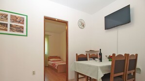 Ein Essbereich mit Tisch, Stühlen, einem Fernseher und einer Wanduhr.