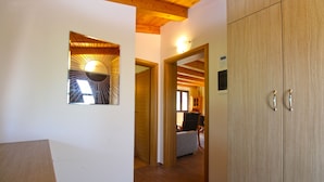 A hallway with wooden flooring, a mirror with a sunburst design, and a wooden wardrobe. - House 1319 (Liznjan)