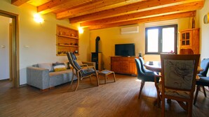 A cozy living room with wooden beams, a sofa, chairs, a TV, and a fireplace. - House 1319 (Liznjan)
