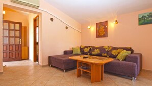 Un salón con sofá, una mesa de centro y una puerta que da a otra habitación.
