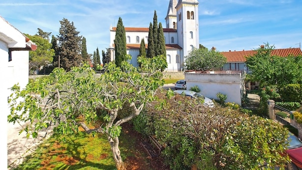 Una iglesia con un campanario, rodeada de árboles y un pequeño edificio.
