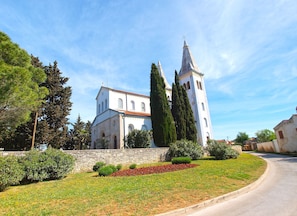 Una iglesia con un campanario alto y un muro de piedra al frente.