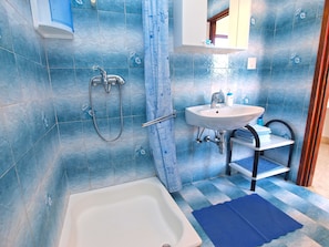 A bathroom with a bathtub, a sink, and a shower. - Apartment 1334 (Medulin)