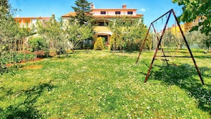 A large house with a garden, a swing set, and a clear blue sky. - Apartment 1334 (Medulin)