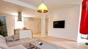 A modern living room with a sofa, a coffee table, a TV, and a punching bag. - House 1338 (Pula)