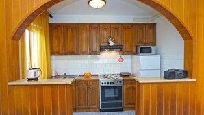 A compact kitchen with wooden cabinets, a stove, a microwave, and a kettle. - Apartment 1341 (Pula)