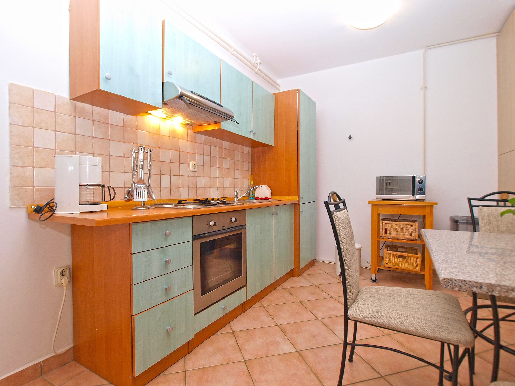 A compact kitchen with a gas stove, oven, and a microwave on a small table.