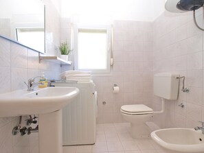 A bathroom with a sink, toilet, bidet, and a washing machine. - Apartment 1346 (Pula)