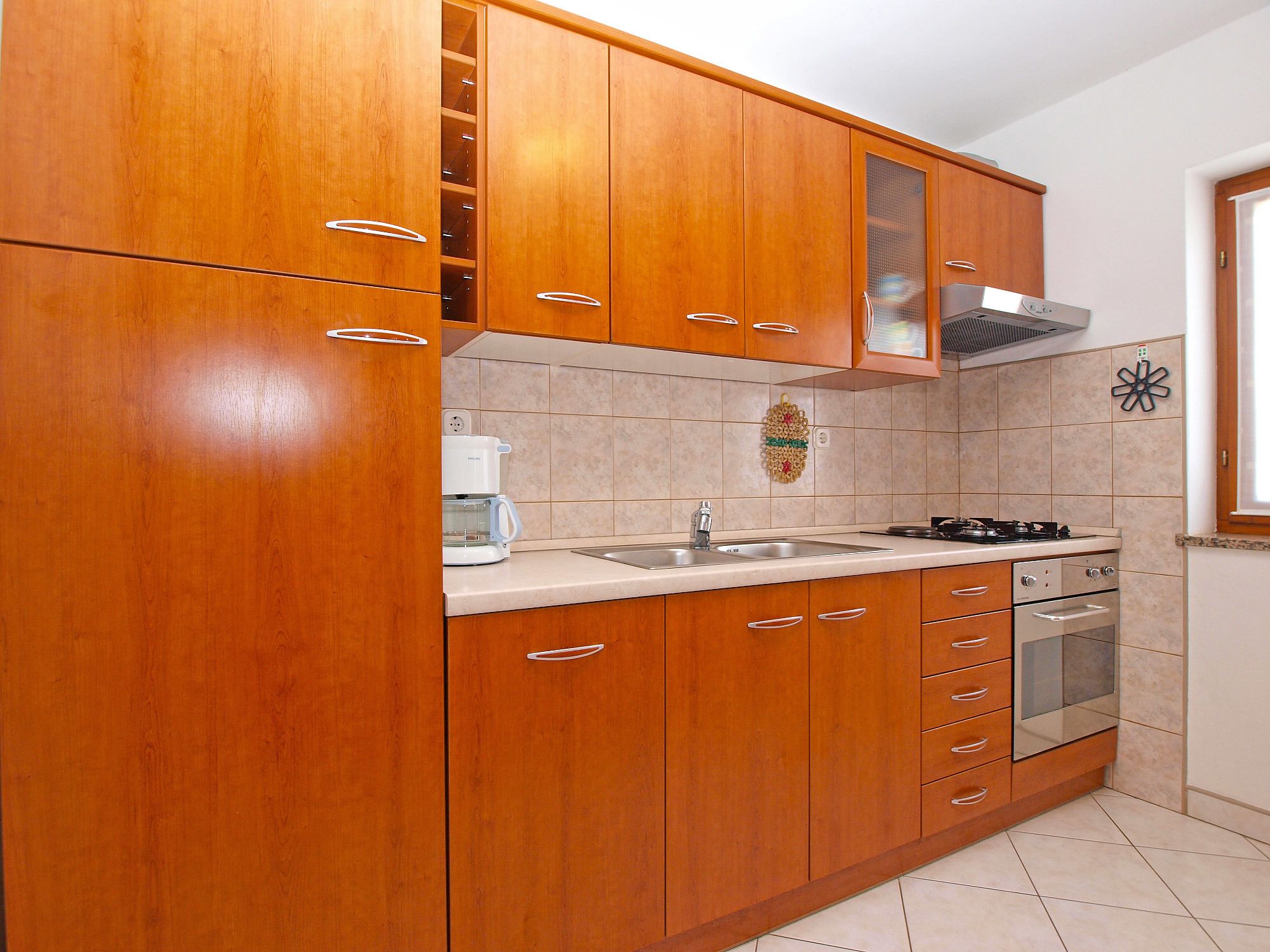 A kitchen with wooden cabinets, a coffee maker, a stove, and a sink.