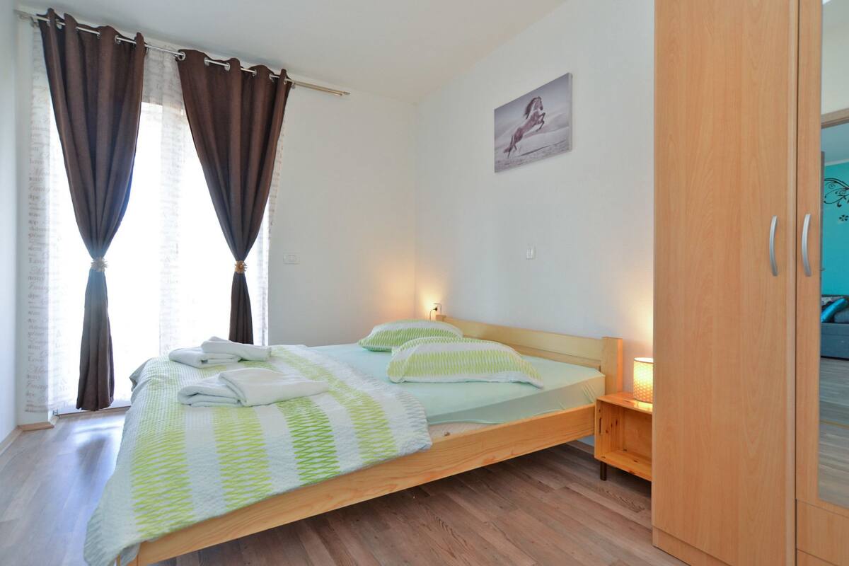 A single bed with a wooden frame, a bedside table with a lamp, and a wardrobe with a mirror.