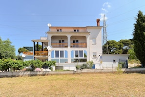 Ein zweigeschossiges Gebäude mit Balkon und Satellitenschüsseln.