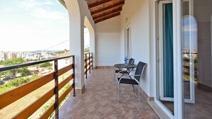 A balcony with a wooden railing, a table with chairs, and a view of the cityscape. - Apartment 1355 (Pula)