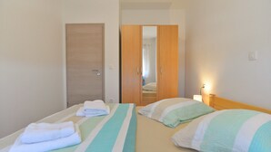 A hotel room with two beds, a wooden wardrobe, and a mirror. - Apartment 1355 (Pula)