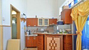 Cozinha compacta com armários de madeira, forno embutido e um pequeno espaço de refeições com mesa e cadeiras.
