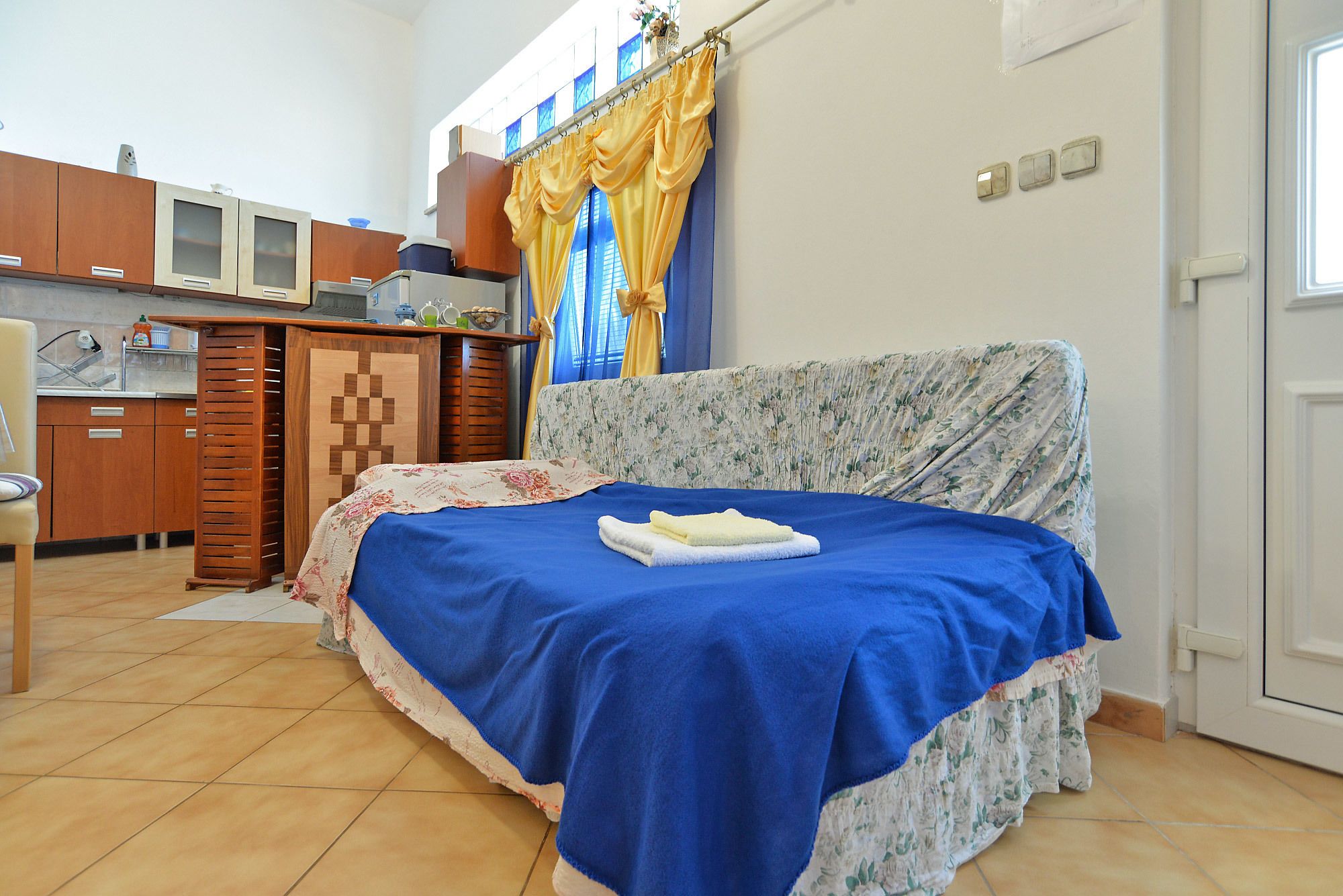 A bedroom with a bed, a small kitchenette, and a bathroom.