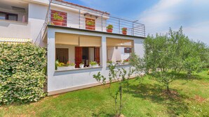 A modern two-story house with a balcony, potted plants, and a small tree in the yard. - Apartment 1375 (Fazana)