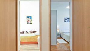 A bedroom with a bed, pillows, a nightstand, and a wall-mounted lamp. - Apartment 1375 (Fazana)