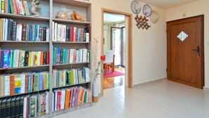 A hallway with bookshelves filled with books, a wooden door, and a mirror on the wall. - Apartment 1375 (Fazana)