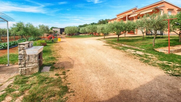 A rural property with a gravel driveway, stone structures, and a large building with a porch. - House 1378 (Vodnjan)
